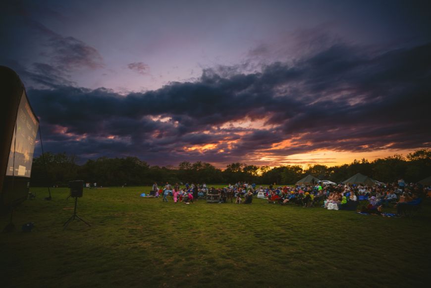 people sat ona a field looking at a screen